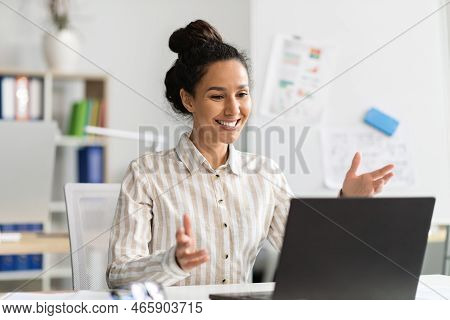 Excited Female Entrepreneur Video Calling Via Laptop, Talking To Webcamera And Smiling, Sitting At W