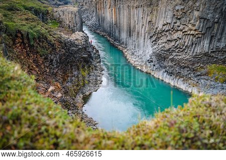 Man Hiker In Red Jacket Visit Studlagil Basalt Canyon, With Rare Volcanic Basalt Column Formations, 