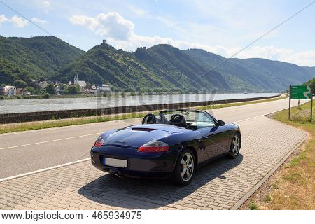 Bad Salzig, Germany - June 26, 2021: Blue Roadster Porsche Boxster 986 With River Rhine Gorge And Ca