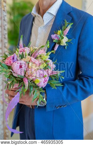 Elegant Man In A Suit Holds A Round Bouquet With Peonies And Eustoma.boutonniere Of Eremurus, White 
