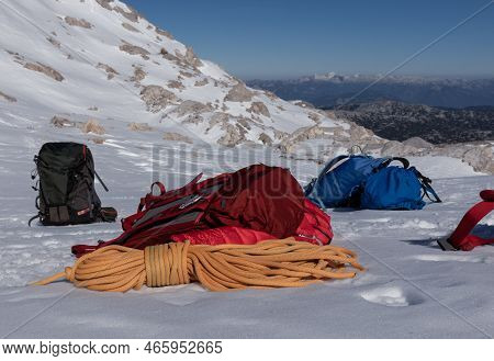 Bright Colored Backpacks And A Rope Lie On A Snowy Slope, Austria, Alps, Dachstein