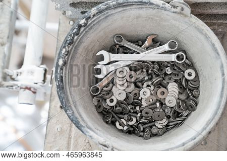 A Bucket Full Of Wrenches, Washers And Stud Bolts Is Placed On The Scaffolding.