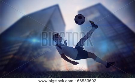 Football player in white kicking against low angle view of skyscrapers
