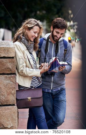 travel couple walking around city on vacation with guide book having fun
