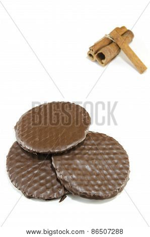 Three Chocolate Biscuits And Cinnamon Sticks Isolated
