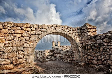 Alarm Ancient Bell Is Visible Through An Ancient Stone Arch On Ruins Of The Ancient Greek City Of Ch