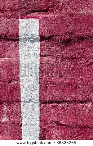 A red painted brick wall with a vertical white painted strip