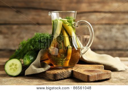 Glass ewer with fresh organic cucumber water on wooden table