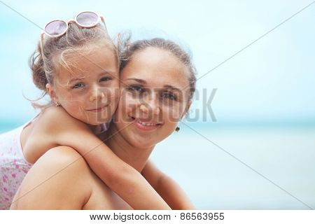Happy family resting at beach in summer, mother with her 5 years old child