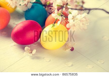 Easter. Colorful Easter eggs with spring blossom flowers over wooden background. Colored Egg Holiday border art design. Vintage toned