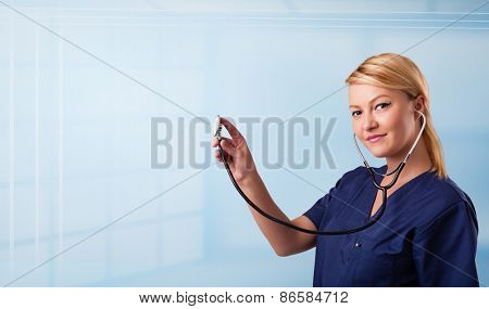 Pretty young nurse in hospital listening to empty copy space with sthetoscope