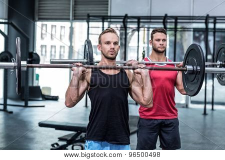 Muscular men lifting a barbell at the crossfit gym
