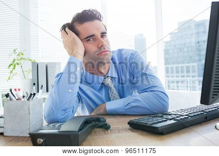 Serious young businessman looking at cameara in office