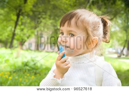 Cute little hellion girl with blue chalk outdoors