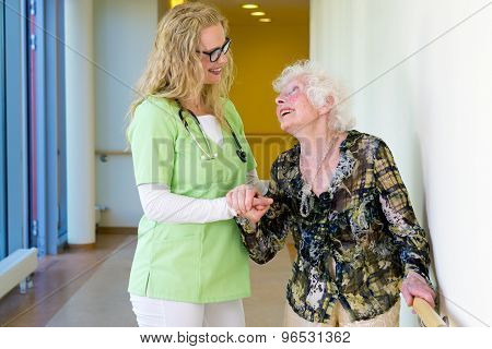 Therapist Assisting Elderly Walking In Hospital