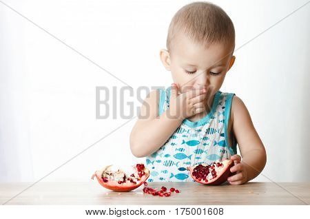 Baby eats a pomegranate ripe and juicy very tasty and joyfully