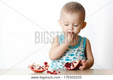 Baby eats a pomegranate ripe and juicy very tasty and joyfully