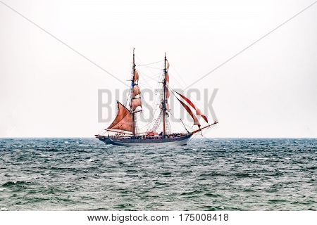 Sailing ship with red sails on the sea. Tall Ship.Yachting and Sailing travel. Cruises and holidays. Postcard and Book cover.