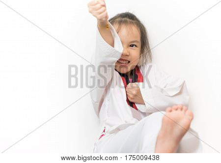 Asian kid is throwing taekwondo kick isoalted on white