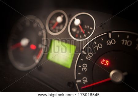 Close up shot of a car's dashboard with the battery icon lit.