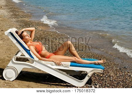 Beautiful woman is lying on the sunbed and enjoying of her vacation at the beach
