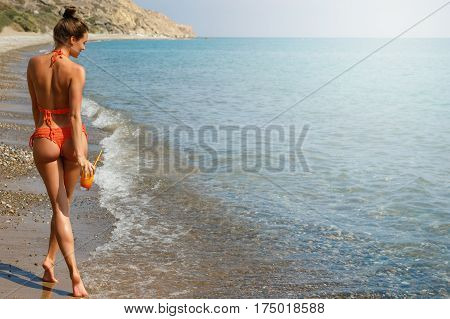 Beautiful woman on the beach with a glass of cocktail