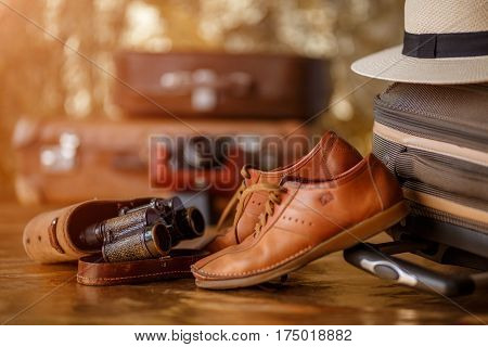 Vintage binoculars and male shoess on suitcase. Shallow depth of field. Travel concept.
