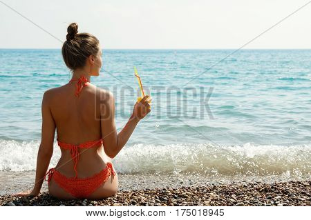 Beautiful woman on the beach with a glass of cocktail