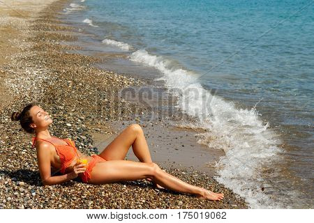 Beautiful woman on the beach with a glass of cocktail