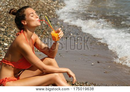 Beautiful woman on the beach with a glass of cocktail