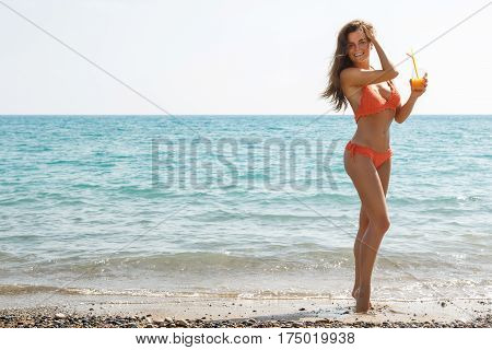Beautiful woman on the beach with a glass of cocktail