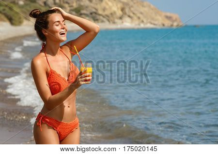 Beautiful woman on the beach with a glass of cocktail