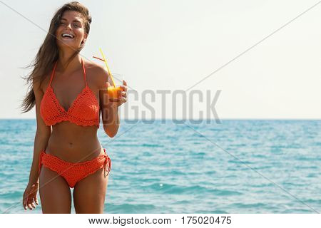Beautiful woman on the beach with a glass of cocktail