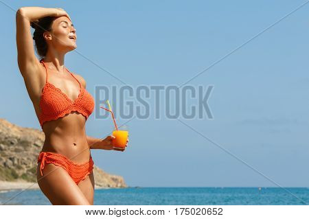 Beautiful woman on the beach with a glass of cocktail