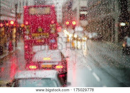 London rain view to red bus through rain-specked window