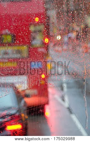 London rain view to red bus through rain-specked window