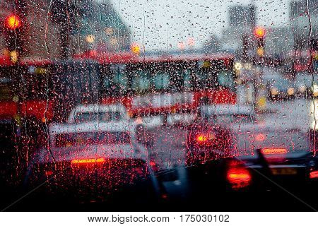 London rain view to red bus through rain-specked window