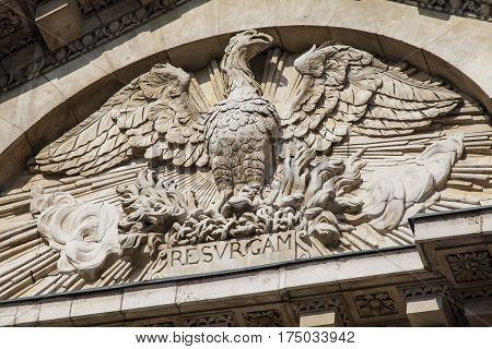 A close-up of the Phoenix sculpture which is located on the southern facade of St. Pauls Cathedral in London. The phoenix can be seen rising from the flames with the inscription RESVRGAM.