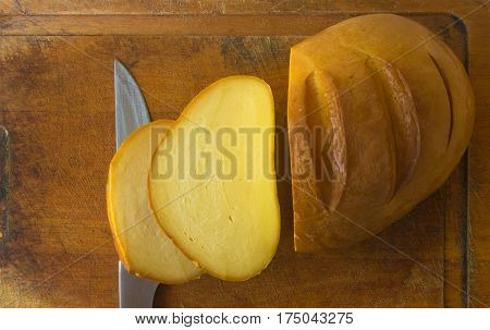 cut head of traditional Adygei cheese handmade with knife on wooden Board
