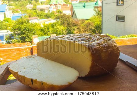 cut head of traditional Adygei cheese handmade with knife on wooden Board