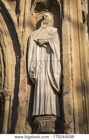 A sculpture of St. Benedict on the exterior of the West Porch of Norwich Cathedral in the historic city of Norwich UK.