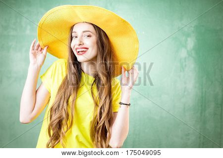 Colorful portrait of a beautiful woman in yellow t-shirt and hat on the green background