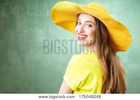 Colorful portrait of a beautiful woman in yellow t-shirt and hat on the green background