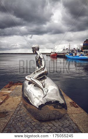 HELSINGOR DENMARK 14 JUNE 2012: Sculpture Han art. Michael Elmgrin and Ingar Dragset. The sculpture mirror repeats the pose of the Mermaid but on the stone sits a naked young man