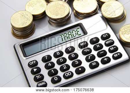few stacks of coins and calculator with text on screen trade