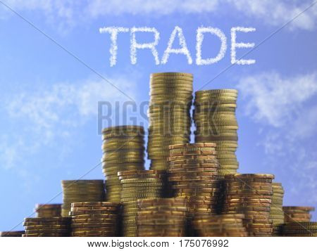Many piles of coins against  blue sky with text trade