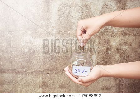 Close up woman's hand putting coin into the bottle
