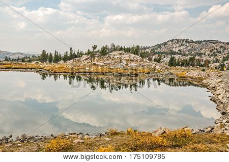 Calm mountain lake with beautiful clouds and reflections and a bit of haze in the distant mountains