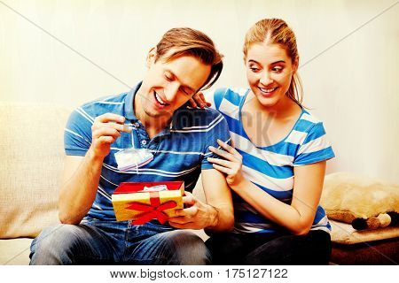 Happy couple - woman hugging her husband who holding gift box and baby shoe