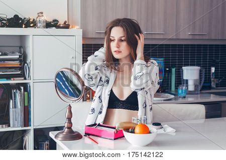 Portrait of young beautiful Caucasian white girl woman in lingerie doing her makeup in front of the mirror in morning at home candid lifestyle natural light toned with filters